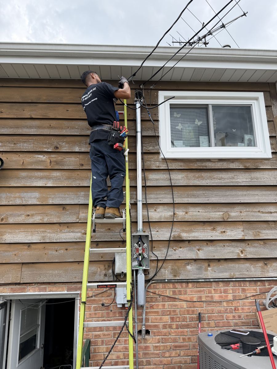 Peak Property Electric technician performing a service upgrade on a ladder